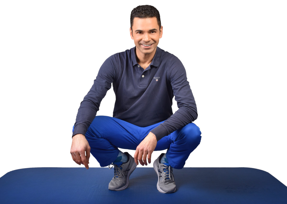 Peter Juhle sitzt auf einer Trainingsmatte und zeigt Übungen für Online Fitnesskurse mit Fokus auf Rücken und Beweglichkeit